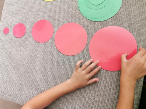 Dziecko układa czerwone koła od najmniejszego do największego – ćwiczenie szeregowania