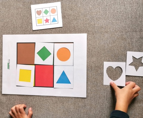 Dziecko układa białe ramki na kolorowej planszy