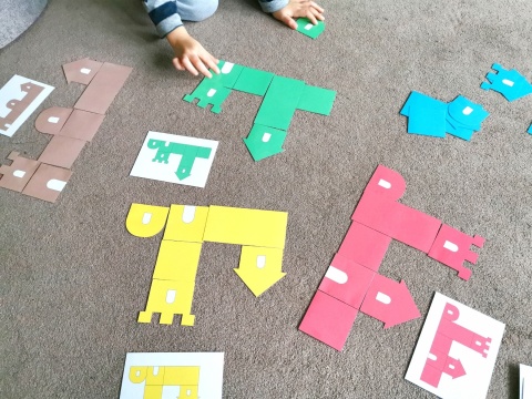 Dziecko układa jednokolorowe zamki z papierowych elementów – układanka lewopółkulowa